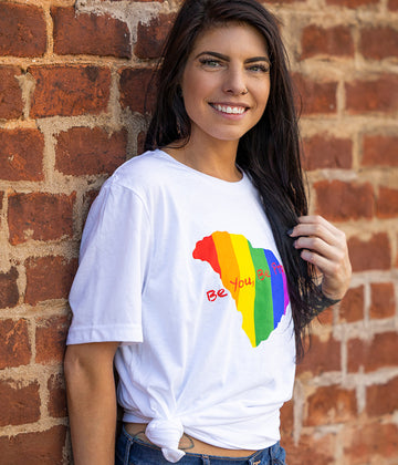 White Tee with State of SC graphic with Pride rainbow colors running vertically and words Be You, Be Proud across the front.