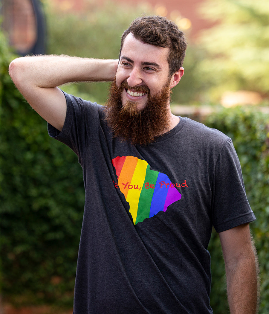 Black Tee with State of SC graphic with Pride rainbow colors running vertically and words Be You, Be Proud across the front.