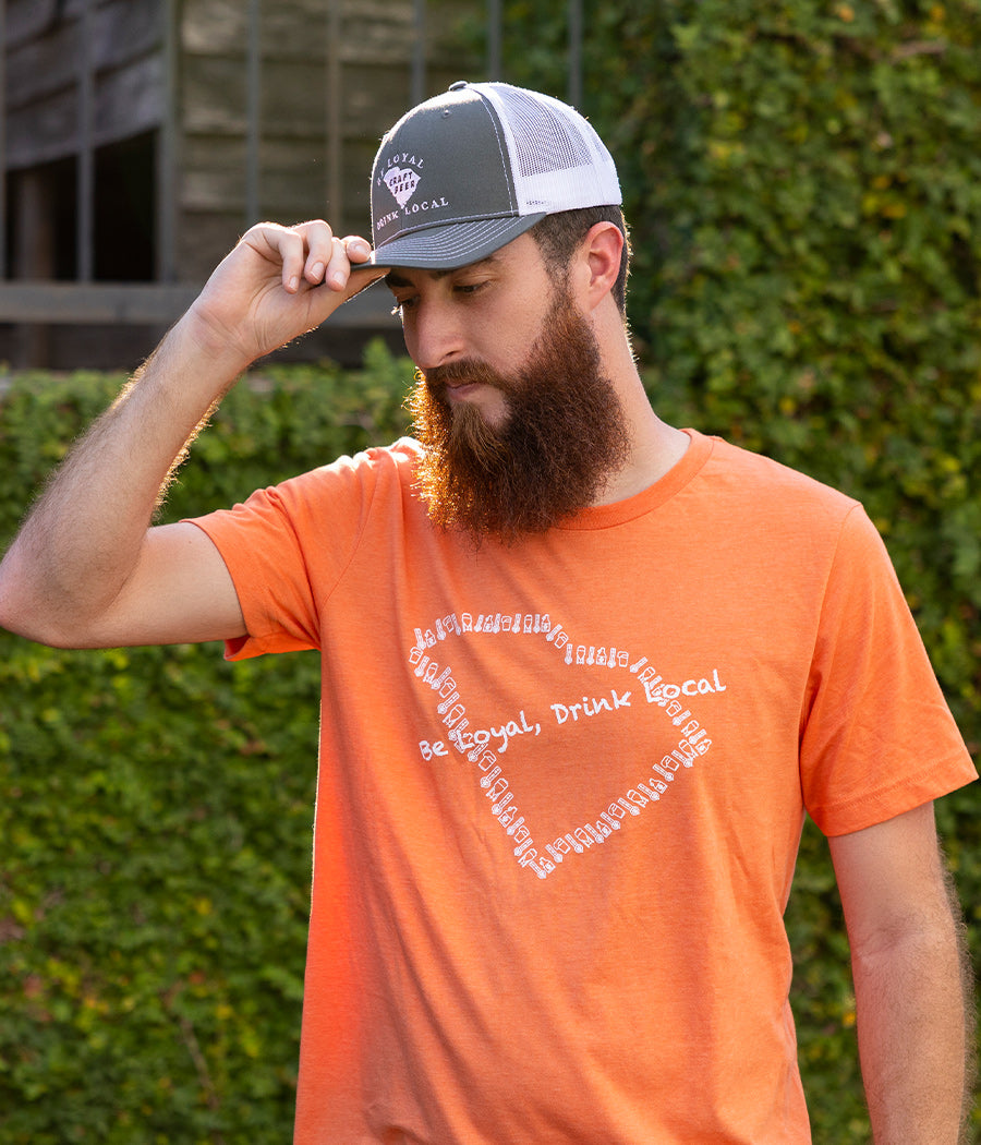 Be Loyal, Drink Local orange T-shirt on model.  This updated premium shirt has the outline of the state of SC made out of brewery icons in white - Tap pull, a glass of beer, fermentation tank, and growler.
